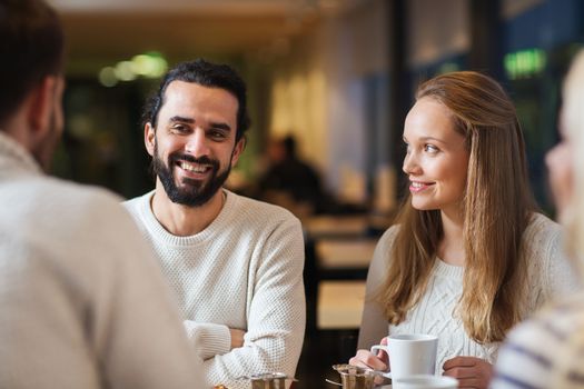 people, leisure, communication, eating and drinking concept - happy friends meeting and drinking tea or coffee at cafe