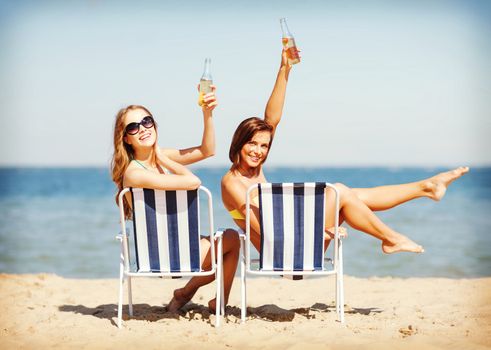 summer holidays and vacation - girls sunbathing and drinking on the beach chairs