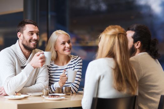 people, leisure, communication, eating and drinking concept - happy friends meeting and drinking tea or coffee at cafe