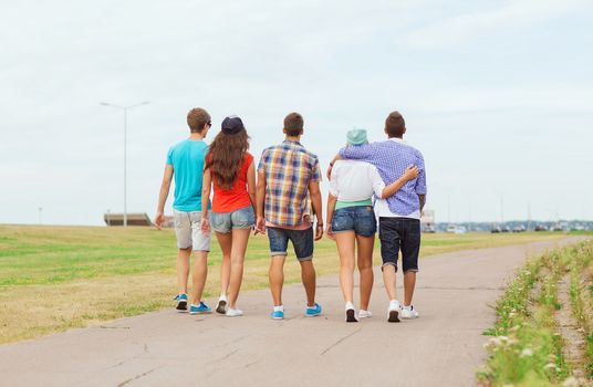 holidays, vacation, love and friendship concept - group of teenagers walking outdoors from back