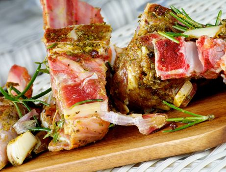 Delicious Raw Lamb Ribs in Marinade of Herbs and Spices with Rosemary and Garlic closeup on Wooden Cutting Board