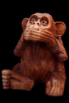The statuette of the monkey. Wooden figurine on a black background.