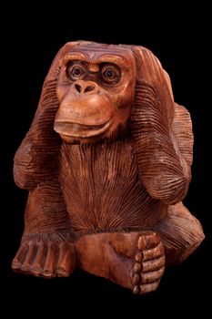 The statuette of the monkey. Wooden figurine on a black background.