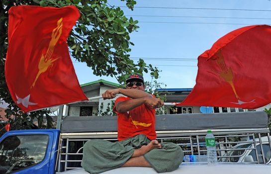 MYANMAR, Yangon : A man shakes two Myanmar flags while tens of thousands of people gather in Yangon on November 1st, 2015 in support of opposition leader of the National League for Democracy party and Nobel Peace Prize Aung San Suu Kyi, one week before general elections. 