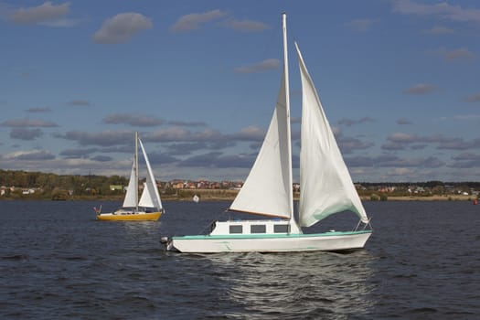 Small boats with white sails floating in the river.