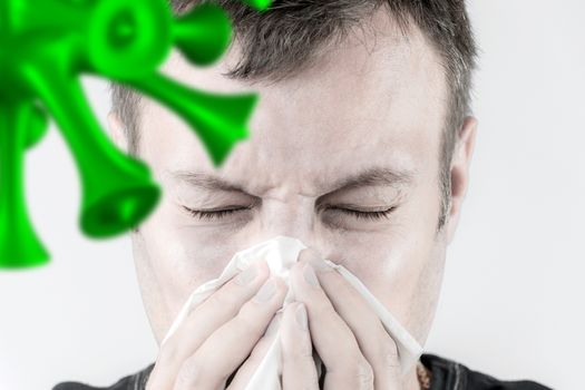 Portrait of a man who is sneezing in a tissue and virus in foreground