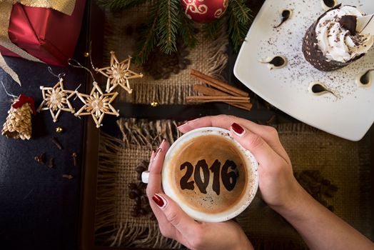 Hands holding mug of coffee close-up, on new year background