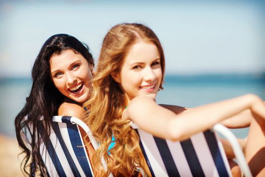 summer holidays and vacation - girls sunbathing on the beach chairs