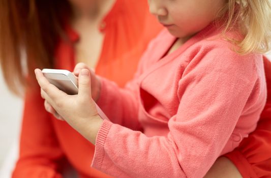 people, family and technology concept - close up of woman and little girl with smartphone