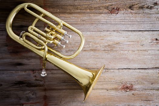 Glossy Baritone Horn Musical Instrument on a Wooden Floor with Copy Space on the Right Side.