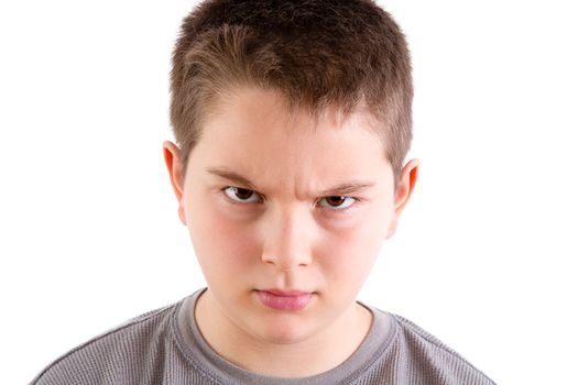 Head and Shoulders Close Up Portrait of Young Boy Looking at Camera with Stern and Disapproving Expression and Furrowed Brow in front of White Background