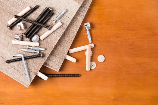 High Angle Still Life Close Up of Various Pieces of Hardware Necessary for Assembling Wooden Shelves on Stained Wood Background with Copy Space