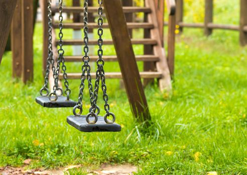 empty swings at playground for child, on green meadow background