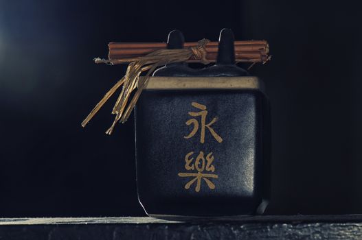 Abstract zen style tea container isolated on black with japanese letters