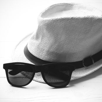 hat and sunglasses on white table black and white color