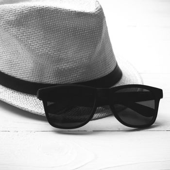 hat and sunglasses on white table black and white color