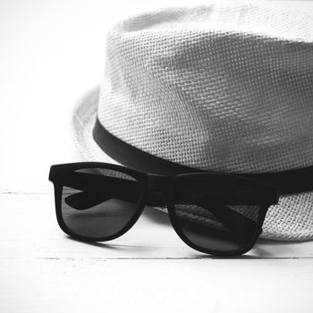 hat and sunglasses on white table black and white color