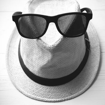 hat and sunglasses on white table black and white color