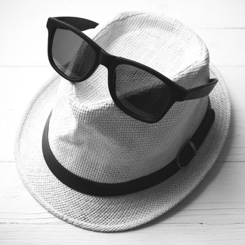 hat and sunglasses on white table black and white color