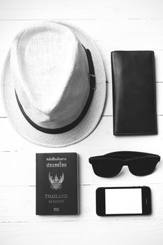 hat sunglasses smart phone and passport over white table black and white color