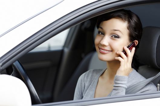 happy young woman talk on cell phone sitting in white car