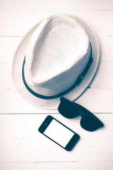 hat sunglasses and smart phone on white table vintage style