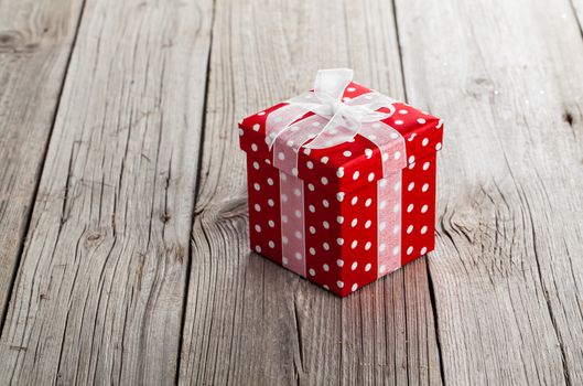 red gift box with bow on wood background