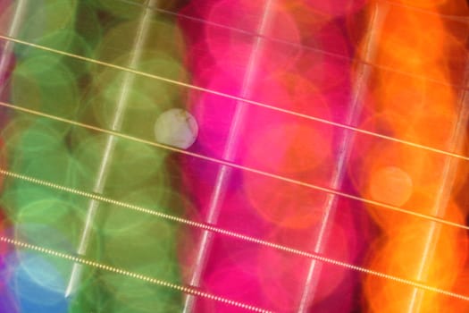 An abstract background of a guitar fretboard through colorful light blurs.