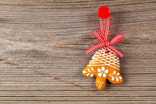 Gingerbread cookie hanging on wooden background. Christmas decoration.