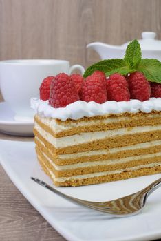 Piece of honey cake with whipped cream and raspberries