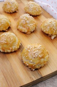 Bun puff pastry with sesame seeds on a wooden board