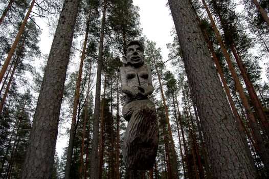 Wooden witch in chains between the trees