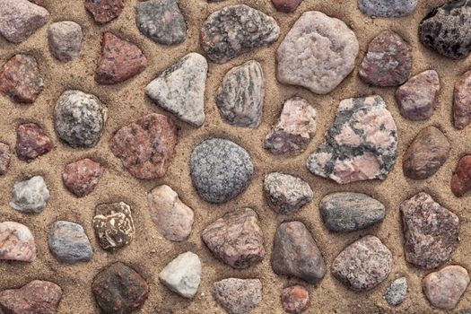 dry colourful stones arranged on sand as background