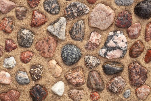 wet colourful stones arranged on sand as background