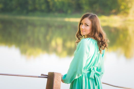The young beautiful girl walks on an old bridge in the warm autumn weather