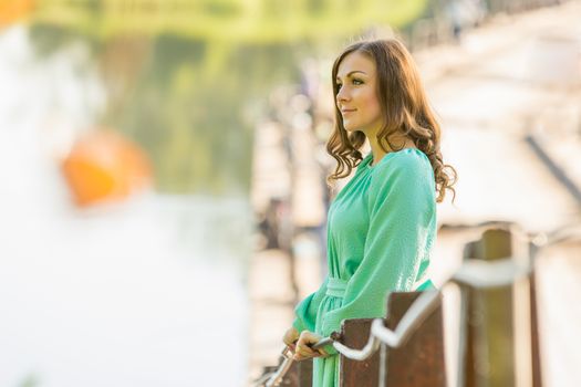 The young beautiful girl walks on an old bridge in the warm autumn weather