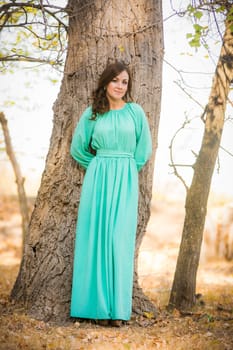Young beautiful girl in a long dress walking in the woods on a warm summer day