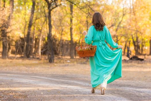 Young beautiful girl in a long dress walking in the woods on a warm summer day