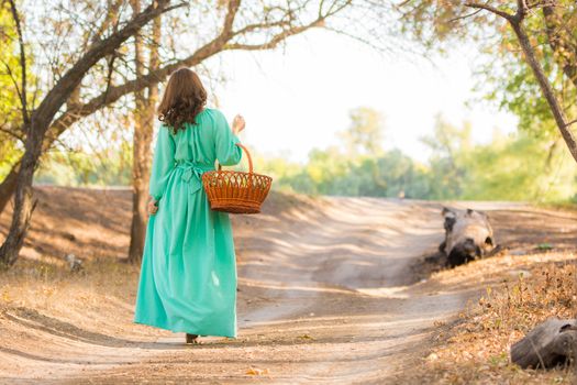 Young beautiful girl in a long dress walking in the woods on a warm summer day