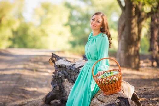 Young beautiful girl in a long dress walking in the woods on a warm summer day