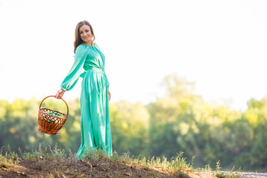 Young beautiful girl in a long dress walking in the woods on a warm summer day