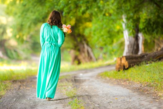 Young beautiful girl in a long dress walking in the woods on a warm summer day