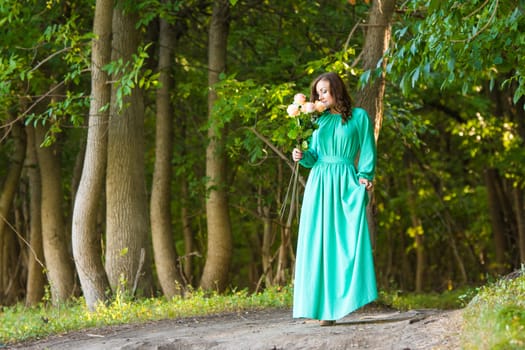 Young beautiful girl in a long dress walking in the woods on a warm summer day