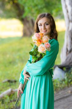Young beautiful girl in a long dress walking in the woods on a warm summer day
