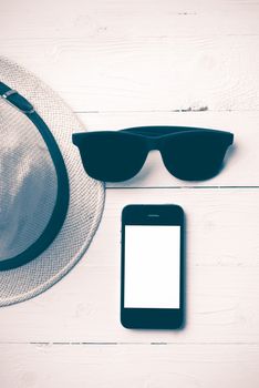 hat sunglasses and smart phone on white table vintage style