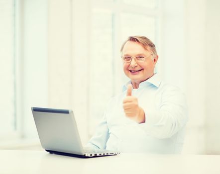 technology, oldness and lifestyle concept - old man in eyeglasses with laptop computer at home showing thumbs up