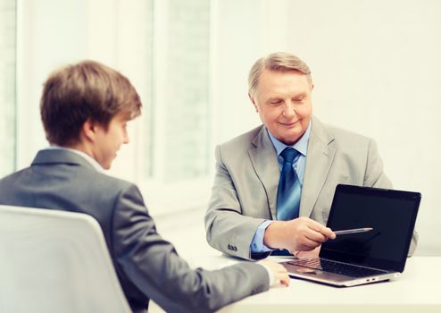 business, advertisement, technology and office concept - older man and young man with laptop computer in office