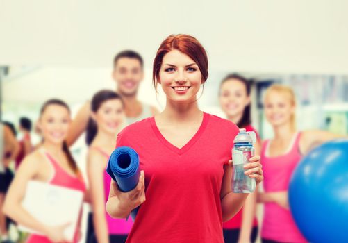 fitness, home and diet concept - smiling teenage girl with bottle of water and yoga mat after exercising at home