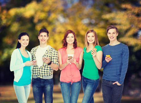 education and modern technology concept - smiling students with smartphones