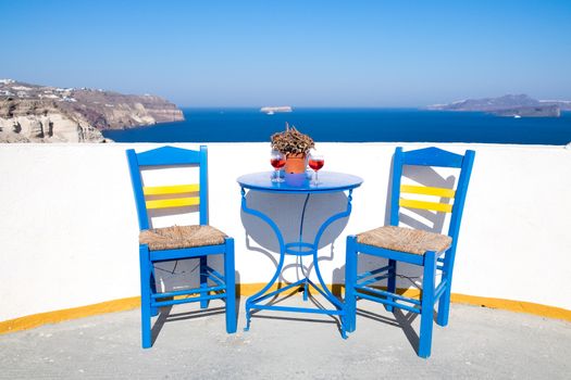 Blue chairs and table on a mediterranean balcony with nice view to the sea, Santorini, Greece